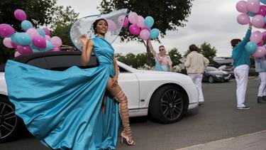 Woman with blue dress standing in front of a car