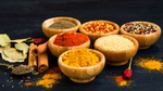 Assorted spices in wooden bowls on a dark background.