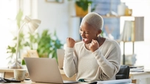 Person celebrating success at a laptop in a bright, cozy office.